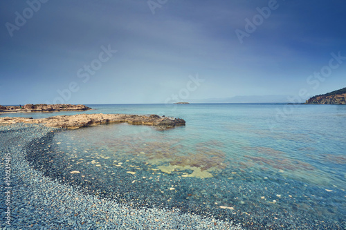 Stones and rocks in forefront with creamy surf ebbing and flowing on Polis beach  Cyprus.