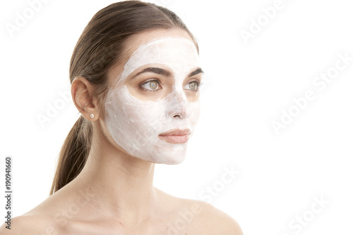 Beauty young female in facial treatment. Close-up shot of a woman with a mask applied to her face. Isolated on white background. 