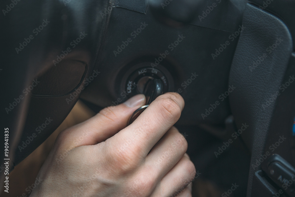 Closeup of man driver hand inserts key in ignition lock