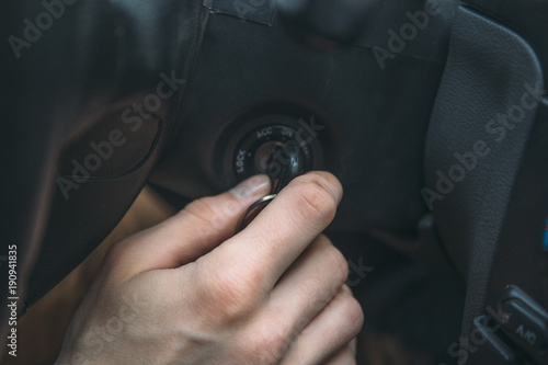 Closeup of man driver hand inserts key in ignition lock