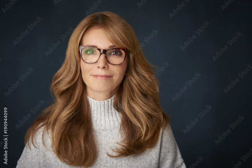 Beautiful smiling mature woman portrait. Happy woman wearing turtle neck sweater and looking confidently at camera while posing at dark backgorund. Beautiful smiling mature woman portrait. Happy woman wearing turtle neck sweater and looking confidently at camera while posing at dark backgorund.