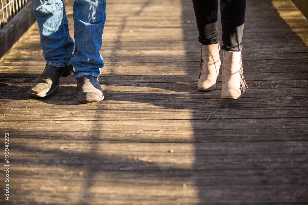 couple walking on wooden walkway boots and pants only, no faces.