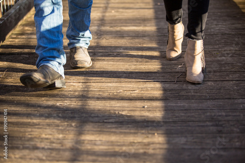 couple walking on wooden walkway boots and pants only, no faces.