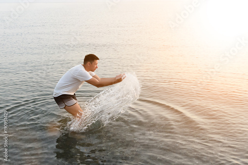 a man stands knee-deep in water and Squirting squatting is in profile