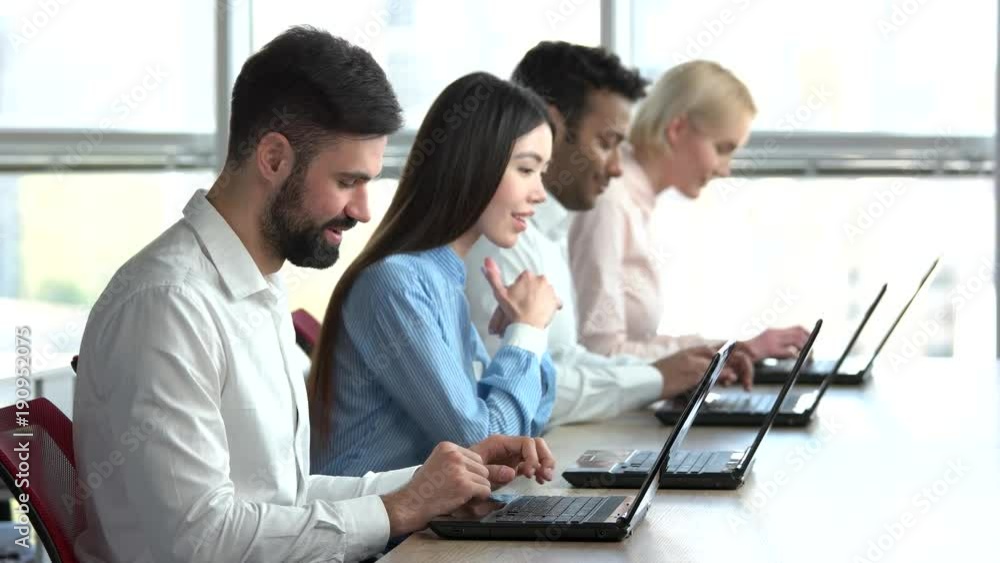 People sitting in office and working on laptops. Team of online traders working together, huge windows background. People sitting in office and working on laptops. Team of online traders working together, huge windows background.