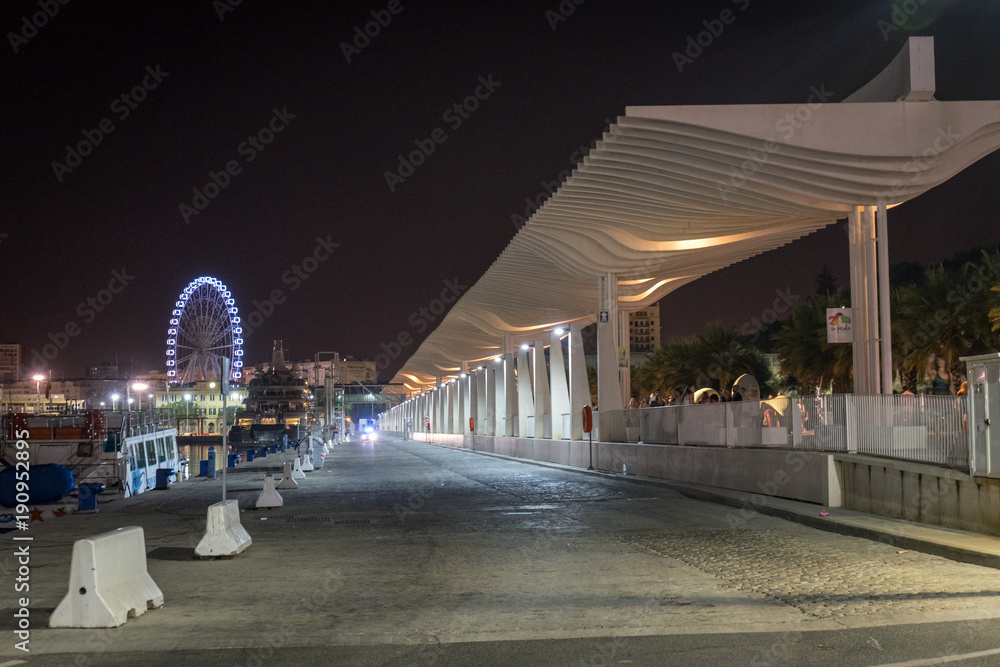 Fototapeta premium The walking path illuminated with the giant wheel with light and illumination at Malaga, Spain, Europe