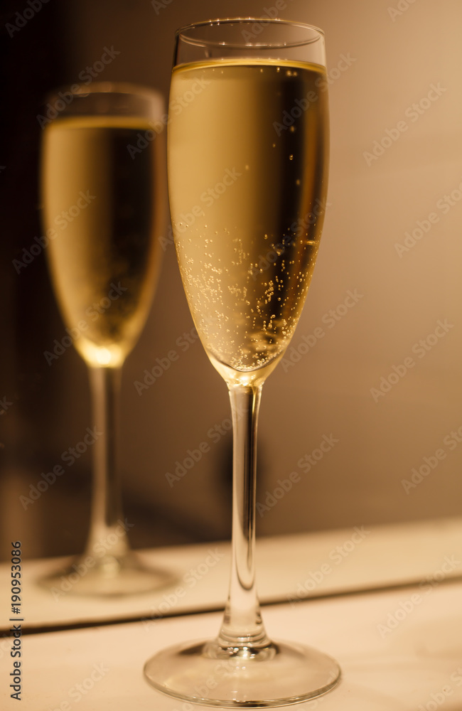 Glass of champagne with reflection in mirror Glass of champagne with reflection in mirror