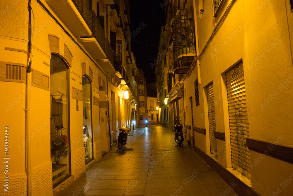 Cobblestone street lit with street lamps at night in Malaga, Spain, Europe