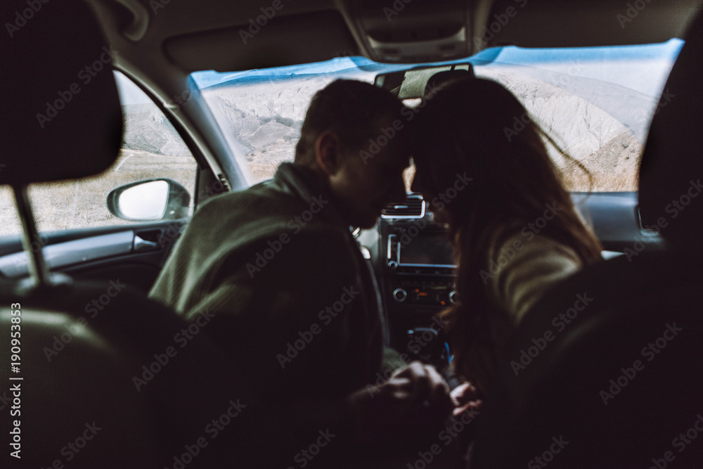 silhouette of a loving couple, of travelers in a car on a background of mountains