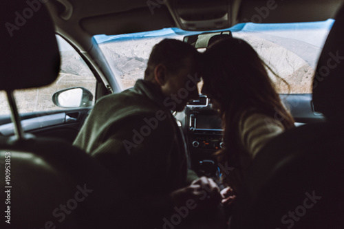 silhouette of a loving couple, of travelers in a car on a background of mountains © aksinya1991
