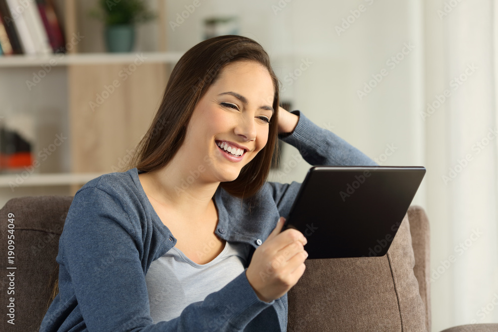 Happy housewife watching media in a tablet at home Happy housewife watching media in a tablet at home
