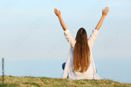 Satisfied woman raising arms watching sky