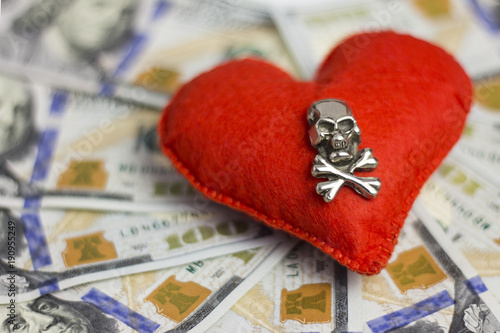 Small DOF. Dollars, heart, death. Concept Piracy and feelings, Wedding contract, dangerous love for money, terrible Valentine's Day. Close-up. photo