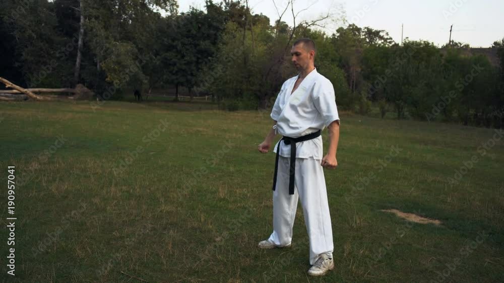 The guy in White Kimono Engages Karate Kyokushinkai Early In the morning in the City Park The guy in White Kimono Engages Karate Kyokushinkai Early In the morning in the City Park