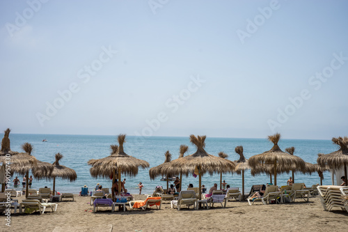 Holiday scene at the malagueta beach with palm roofs on a summer day with the ocean in the background in Malaga, Spain, Europe
