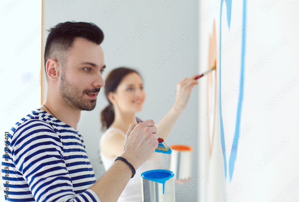 Portrait of happy smiling young couple painting interior wall of new house. young couple Portrait of happy smiling young couple painting interior wall of new house. young couple