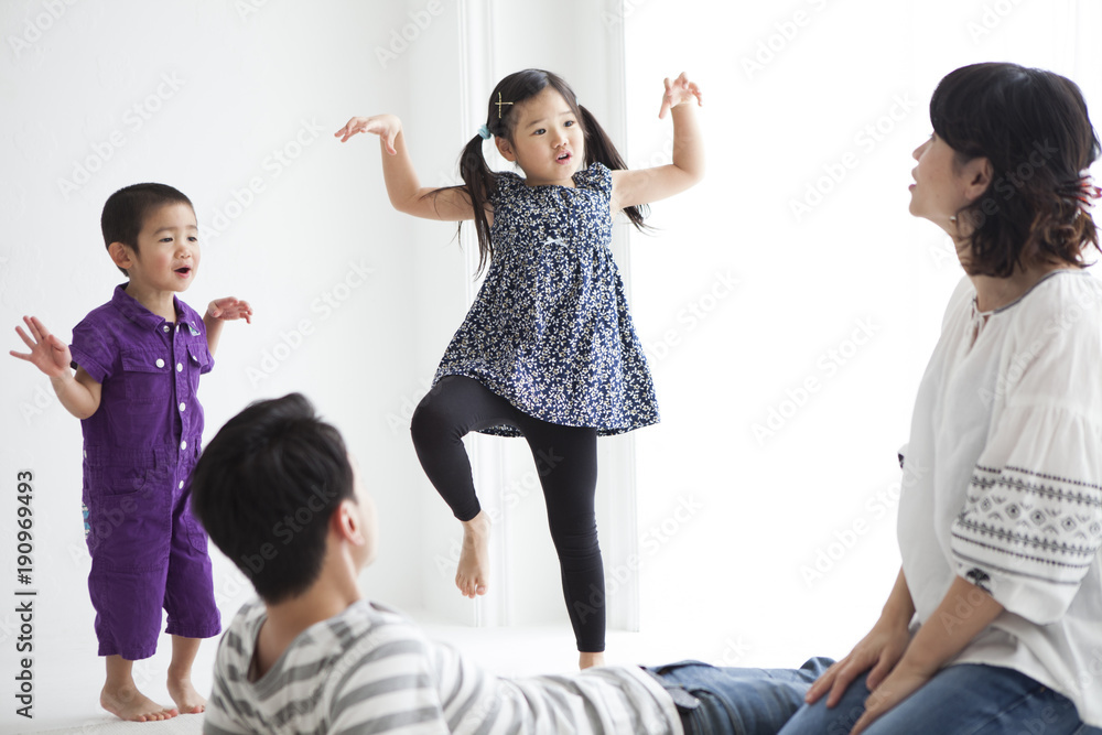 Obraz premium 歌って、踊っている女の子と男の子。笑顔で見守るお父さんとお母さん。