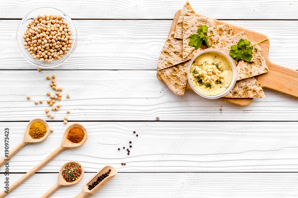 Serve hummus. Bowl with dish near pieces of crispbread on white wooden background top view copy space Serve hummus. Bowl with dish near pieces of crispbread on white wooden background top view copy space