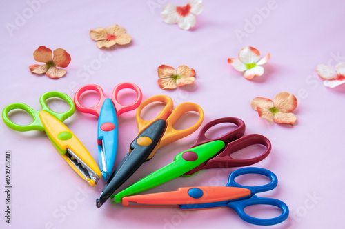 Multicolored scissors and flowers on a pink background