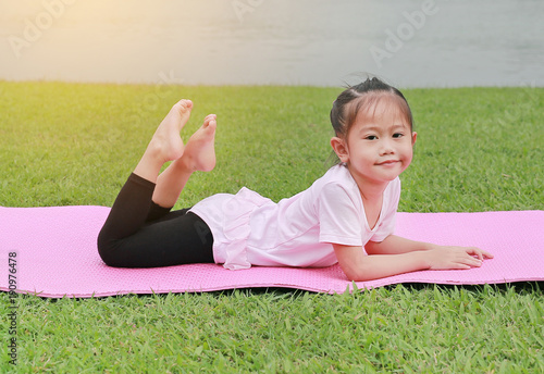 Cute little asian child girl doing yoga in the public park.