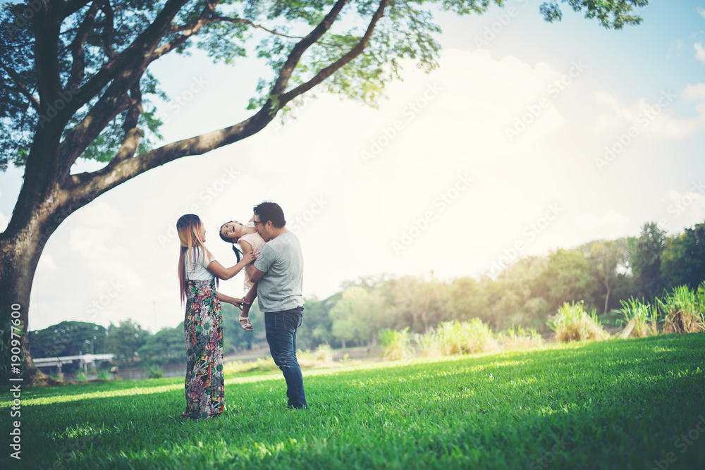 Happy family in the park, Father and Mother playing with daughter, relax family time Happy family in the park, Father and Mother playing with daughter, relax family time