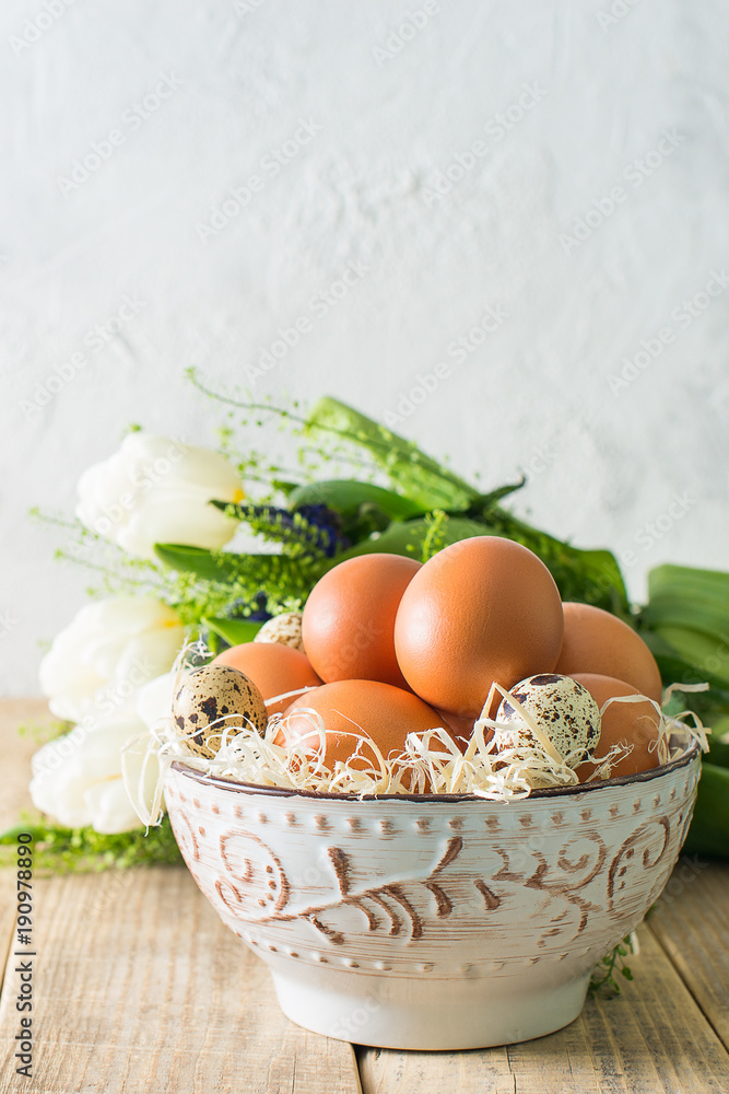 Spring flowers with eggs in bowl on wooden texture, easter theme Spring flowers with eggs in bowl on wooden texture, easter theme