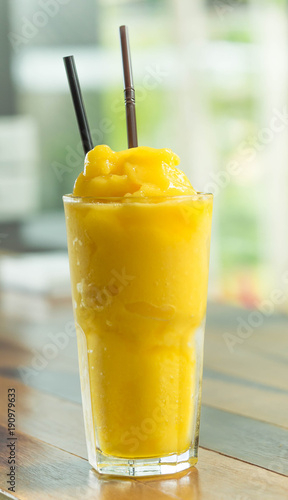 Mango smootie with green background on wood table