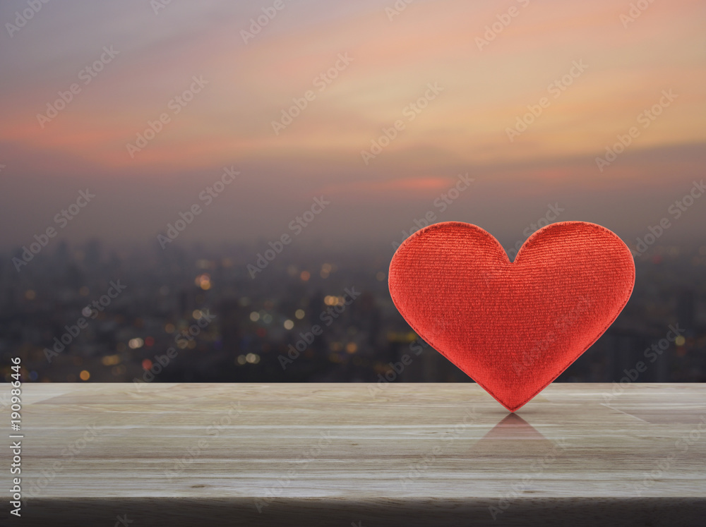 Fabric red love heart shape on wooden table over blur of cityscape on warm light sundown, Valentines day concept Fabric red love heart shape on wooden table over blur of cityscape on warm light sundown, Valentines day concept