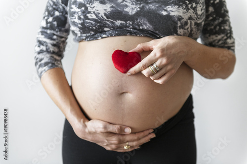 Wallpaper Mural Pregnant woman holding a heart in front of her baby bump Torontodigital.ca
