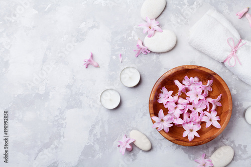 Aromatherapy, spa, beauty background with massage pebble, perfumed flowers water and candles on stone table top view. Relaxation and zen like concept. Flat lay style.