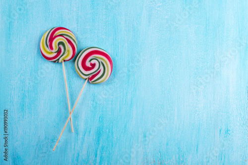 Two round lollipops with many colors in a spiral on turquoise copy space background