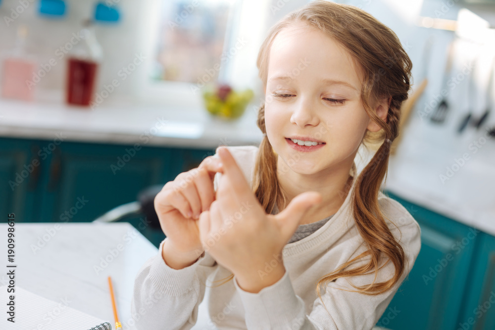 Learning to count. Nice alert blond girl smiling and looking at her hands while counting on her fingers