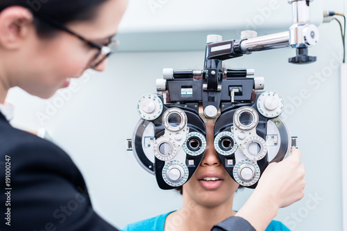 Valokuva Optometrist and woman at eye examination with phoropter