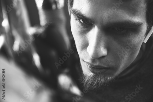 A young guy, beats a tattoo on the hand of the girl in a tattoo parlor, rotary tattoo machine, black ink, close up