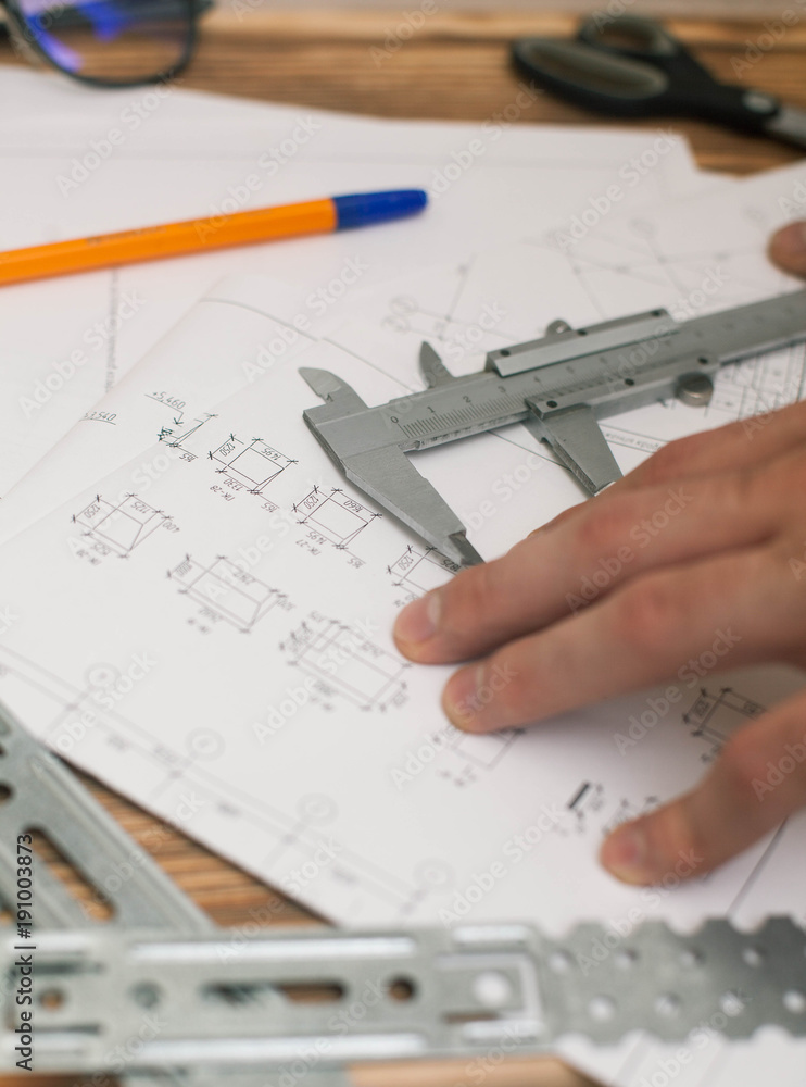 Construction plans, pen and measure tools on wooden board background, top view, closeup Construction plans, pen and measure tools on wooden board background, top view, closeup