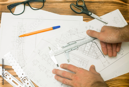 Construction plans, pen and glasses on wooden board background, top view, closeup