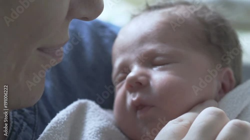 Woman kissing her newborn baby while he is yawning 

