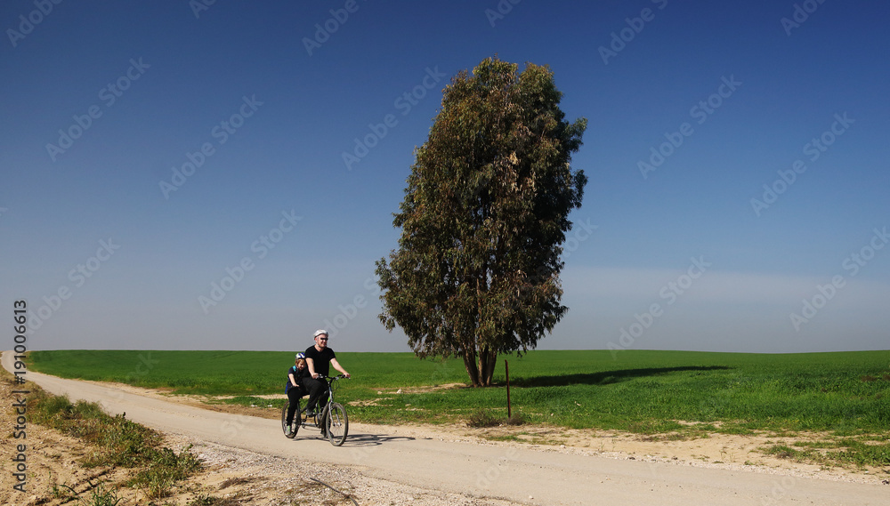 Fototapeta premium father and son ride a tandem bike