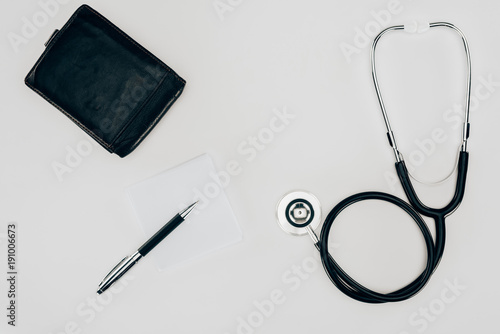 top view of medical stethoscope, wallet and pen on white surface
