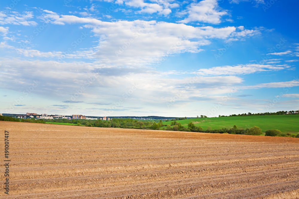 spring of landscape with ploughed field and blue sky