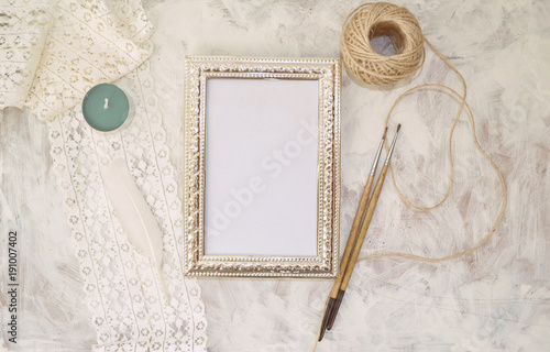 Vintage mockup. Vintage silver frame with place for text, lace, twine, brushes, candle and white feather © scarlet_heath