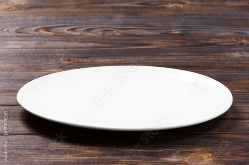 white plate on the wooden brown table. Perspective view