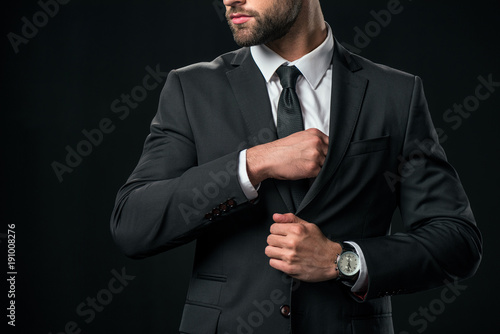 cropped view of businessman taking something from pocket of jacket, isolated on black