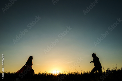 Happy young couple meeting after long time, running into each other with open arms . silhouettes at sunset