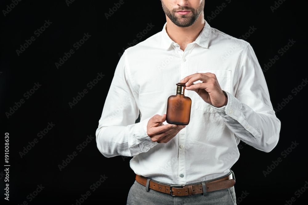 cropped view of businessman in white shirt holding perfumes, isolated on black cropped view of businessman in white shirt holding perfumes, isolated on black