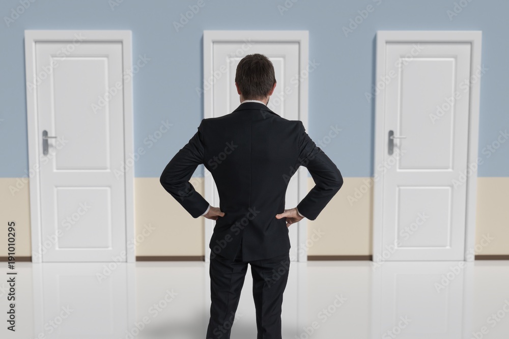 Fotografie Businessman from behind is making decision and selecting the door
