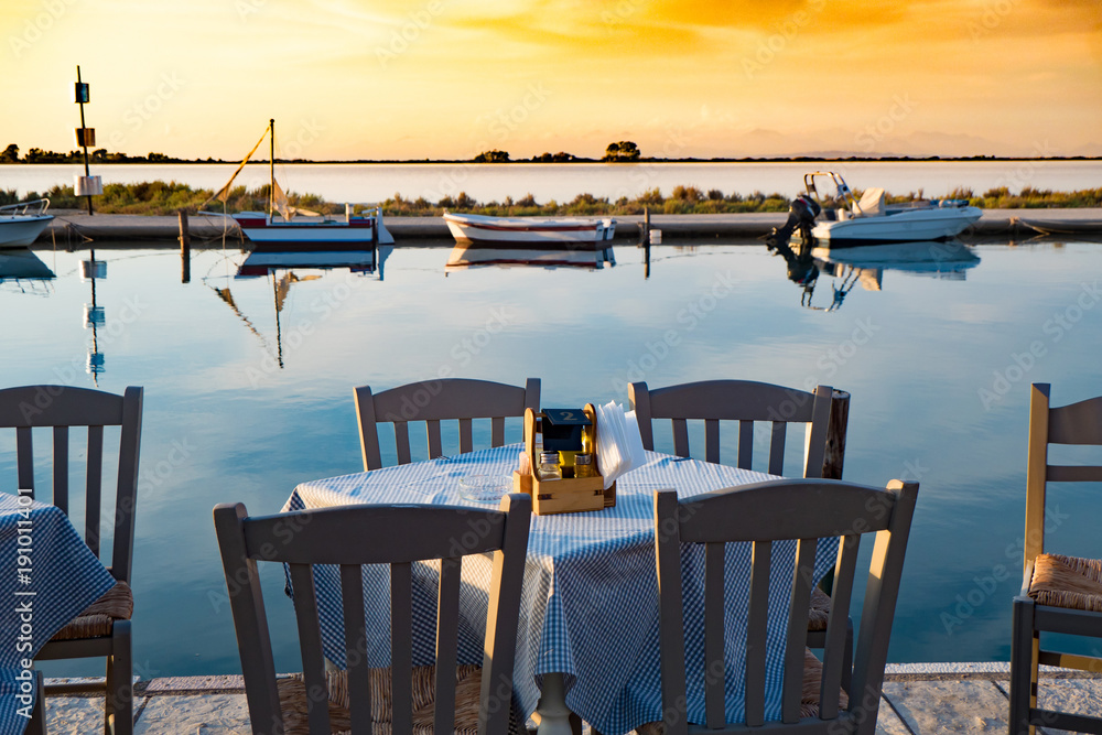 Obraz premium Traditional Greek tavern table near the sea at sunset