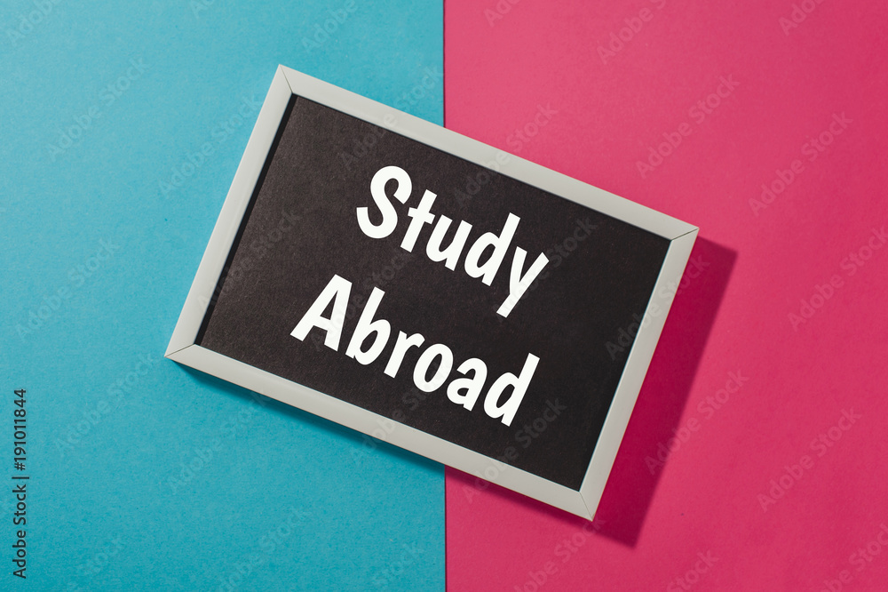 Study Abroad - text on chalkboard on blue and pink bright background. Study Abroad - text on chalkboard on blue and pink bright background.