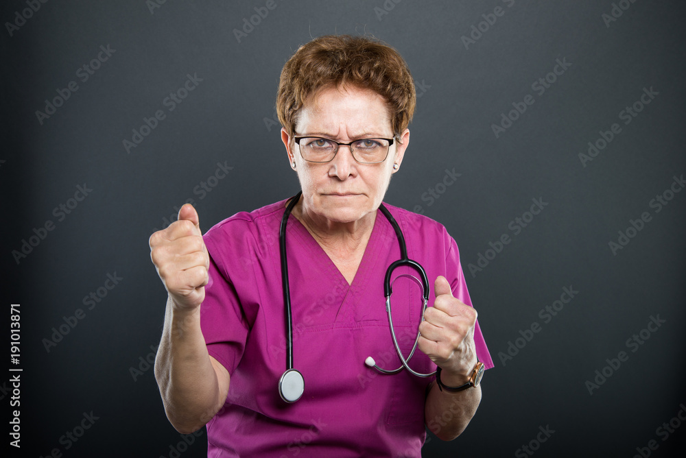 Portrait of senior lady doctor holding both fists Portrait of senior lady doctor holding both fists