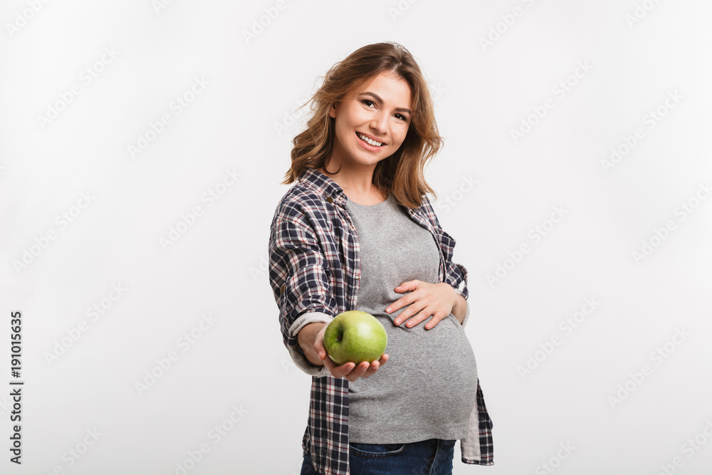 happy pregnant woman holding apple and smiling at camera isolated on white happy pregnant woman holding apple and smiling at camera isolated on white